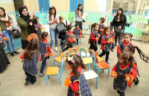 Mães e crianças participam de atividade escolar de dia.